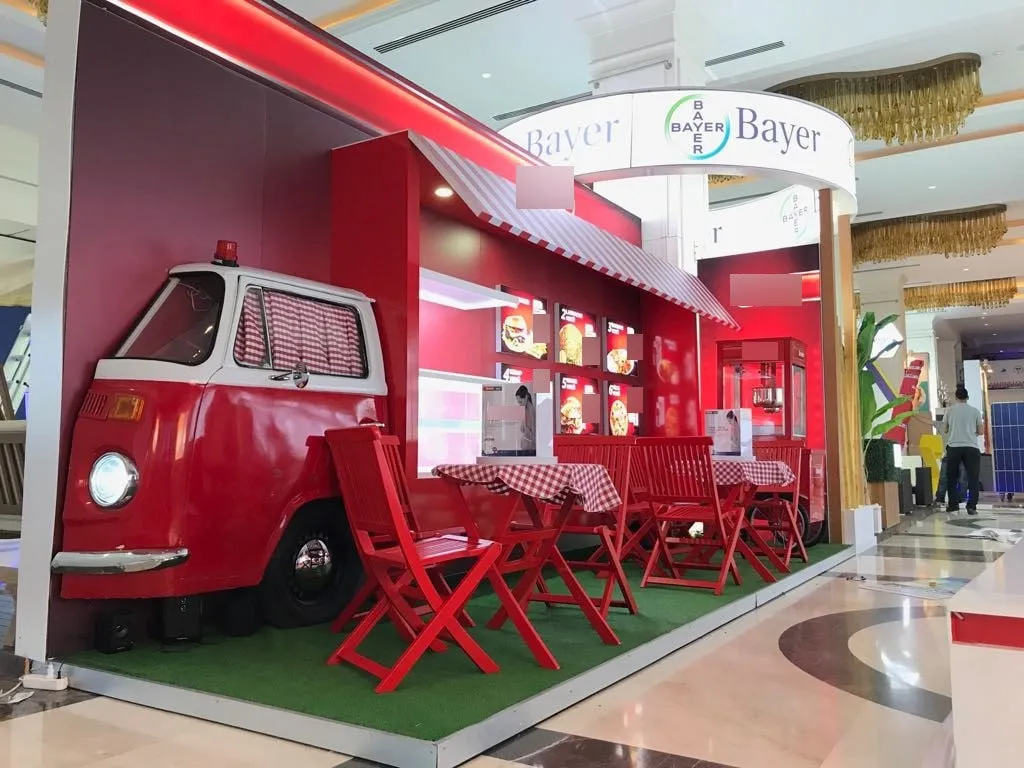 Kırmızı klasik minibüs dekorlu, çim zeminli açık hava etkinlik standı